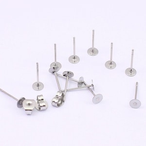 May include: A set of 10 silver earring posts with flat backs. The posts are about 1 inch long and the backs are about 5/16 inch in diameter.