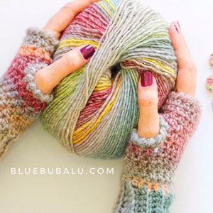 Puede incluir: Un par de guantes sin dedos de ganchillo en un hilo multicolor con una bola de hilo en los mismos colores. El hilo es una mezcla de beige, marrón, rosa y verde. Los guantes están hechos a ganchillo en una puntada texturizada. El texto "BLUEBUBALU.COM" es visible en la imagen.
