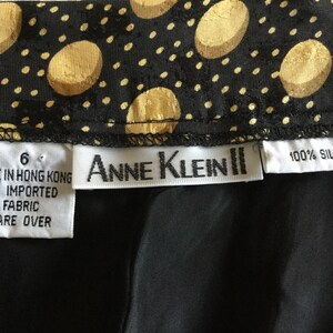 May include: Black silk fabric with a gold polka dot pattern. The label reads "Anne Klein II" and "100% Silk". The tag also indicates the item was made in Hong Kong of imported fabric.