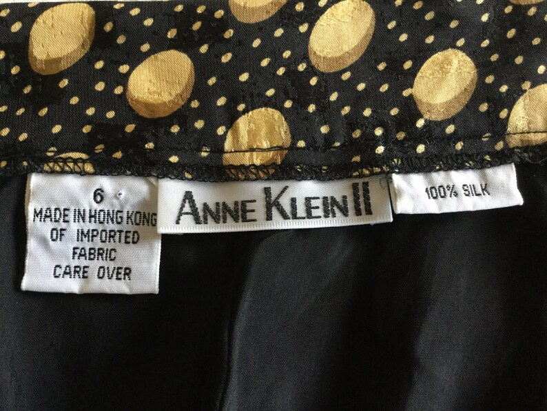 May include: Black silk fabric with a gold polka dot pattern. The label reads "Anne Klein II" and "100% Silk". The tag also indicates the item was made in Hong Kong of imported fabric.