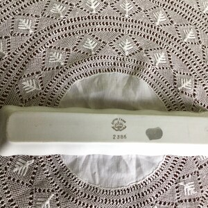 May include: White rectangular ceramic dish with a raised edge. The bottom of the dish has a printed mark that reads "Irish Charm" and "2386".