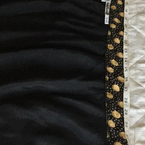 May include: Black dress with a polka dot pattern on the top and trim. The dress is measured with a tape measure, showing a length of approximately 37 inches. The brand tag reads "ANNE KLEIN".