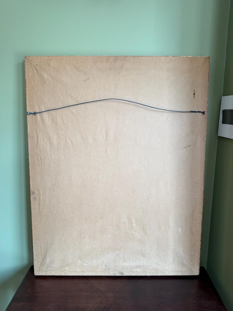 May include: The back of a rectangular picture frame featuring a light brown paper backing. A thin, dark metal hanging wire is attached to the frame with small metal fasteners on each side, creating a curved line across the upper portion.