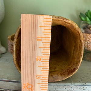 May include: A brown ceramic mug with a speckled glaze. The mug is approximately 4 inches tall and has a rounded shape. A wooden ruler is next to the mug for size reference.