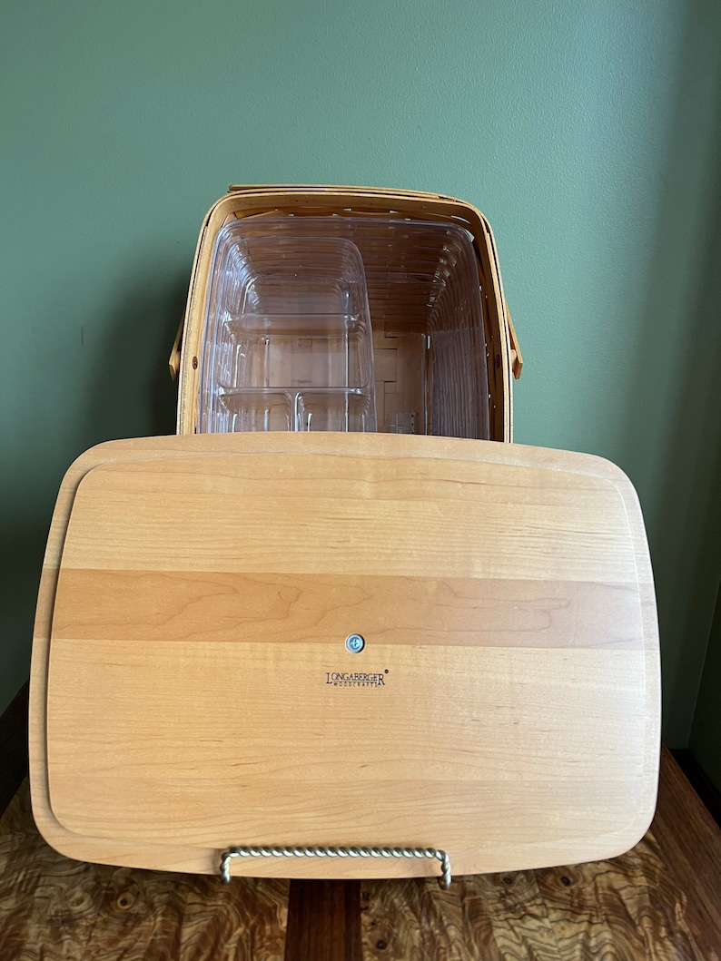 Puede incluir: Una bandeja de servir de madera Longaberger con una cesta de pl&aacute;stico transparente en su interior. La bandeja tiene un acabado de madera clara y el logotipo de Longaberger es visible en la parte inferior.
