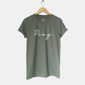 May include: A green t-shirt with the word "Pray" written in white cursive script.