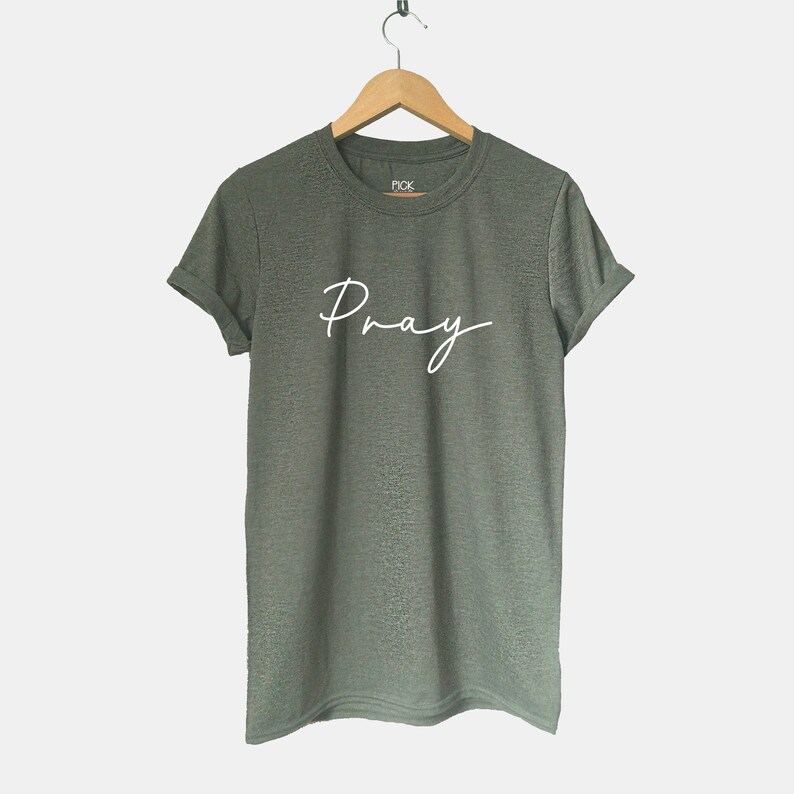 May include: A green t-shirt with the word "Pray" written in white cursive script.
