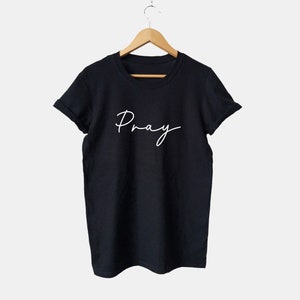 May include: Black t-shirt with white text that says "Pray" in a cursive font.