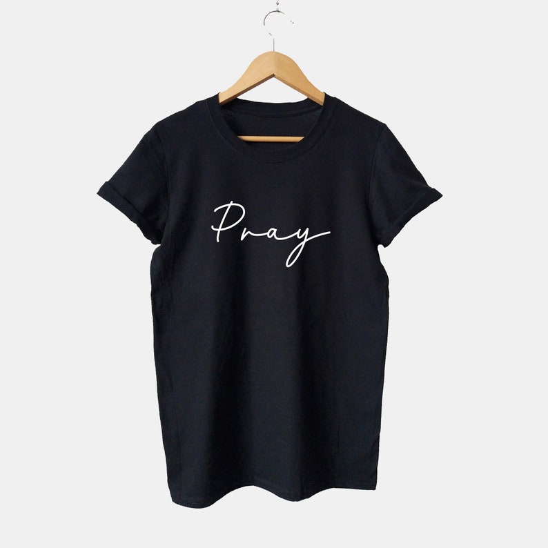 May include: Black t-shirt with white text that says "Pray" in a cursive font.