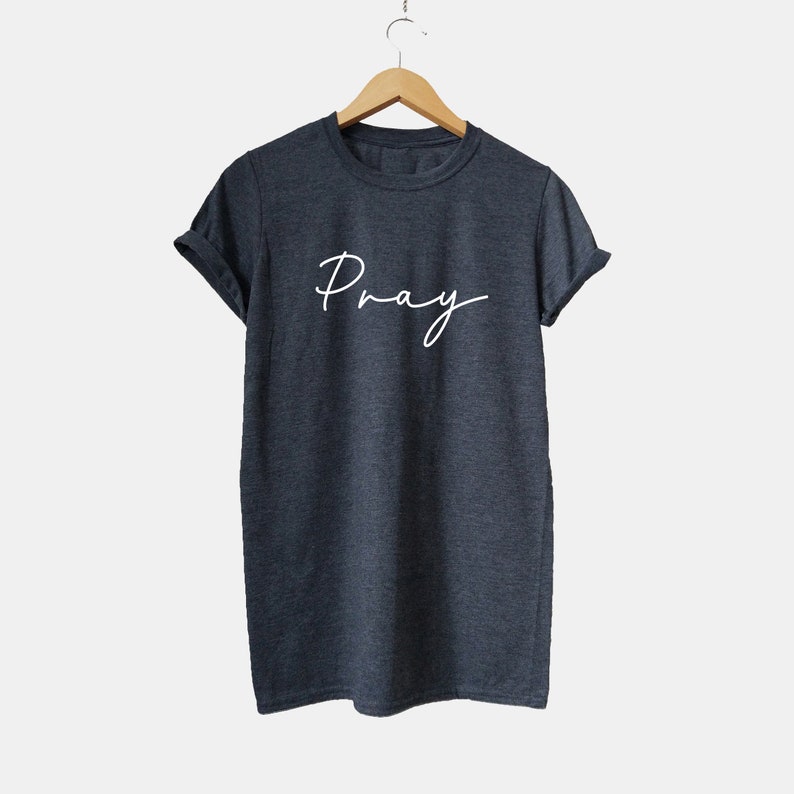 May include: A dark gray t-shirt with the word "Pray" written in white cursive script.