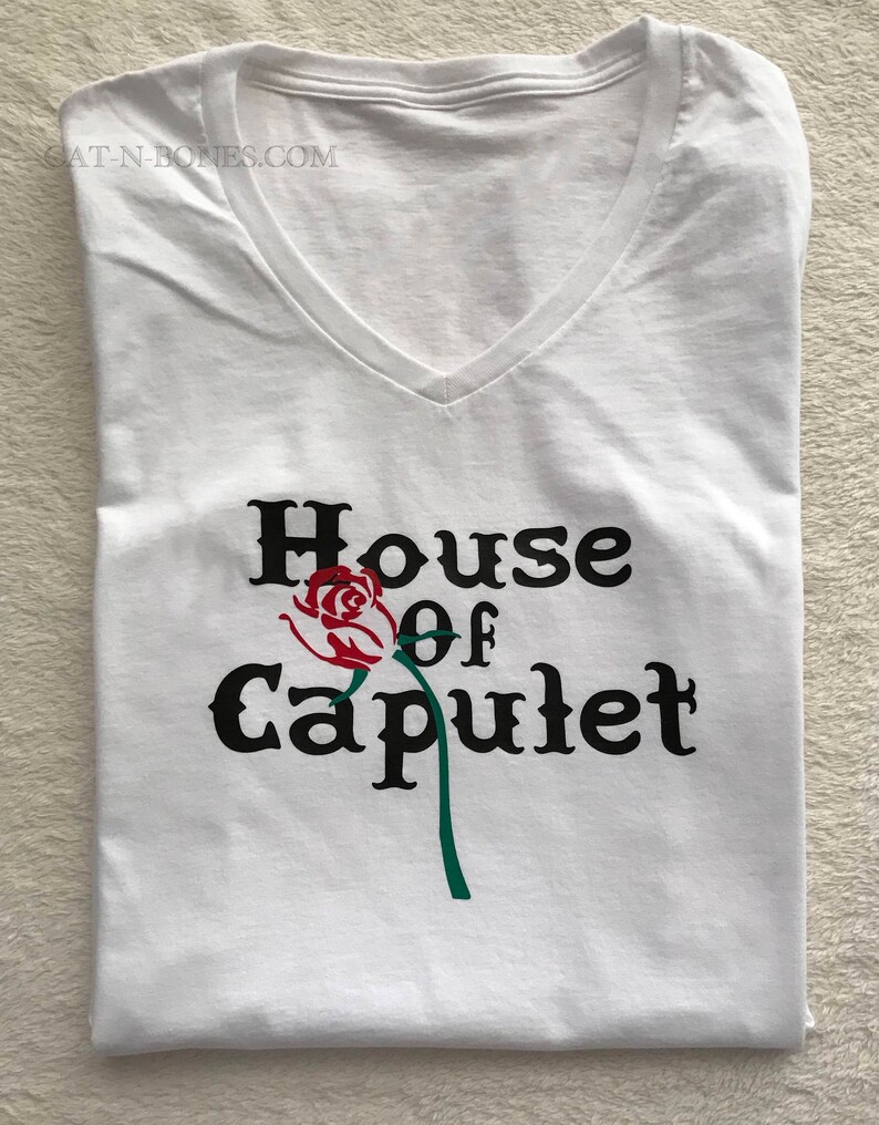 May include: White v-neck t-shirt with a black graphic that says "House of Capulet" with a red rose and green stem.