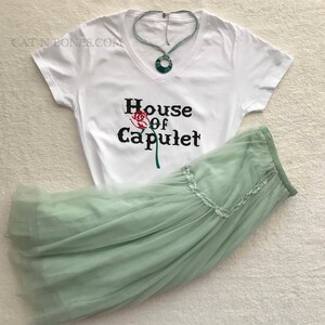May include: White t-shirt with a black graphic that says "House of Capulet" with a red rose illustration. A light green tulle skirt is also pictured.