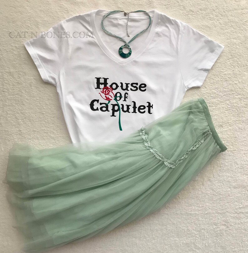 May include: White t-shirt with a black graphic that says "House of Capulet" with a red rose illustration. A light green tulle skirt is also pictured.