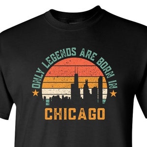 May include: Black t-shirt with a vintage-style graphic that says "Only Legends Are Born In Chicago" with a skyline silhouette and a sunset design.