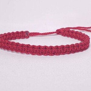 Puede incluir: Un brazalete trenzado rojo con un dije de coraz&oacute;n plateado y cierre ajustable.