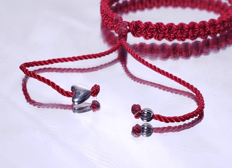 Puede incluir: Pulsera de cord&oacute;n trenzado rojo con abalorios de coraz&oacute;n y cuentas plateadas. La pulsera es ajustable con un nudo deslizante.