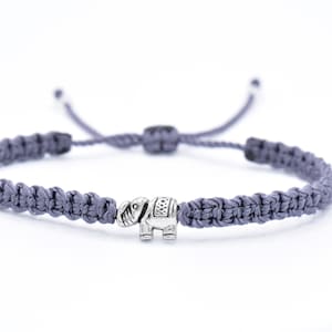 May include: A gray braided bracelet with a silver elephant charm.