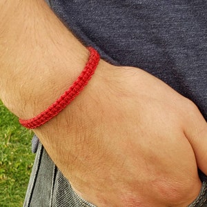 May include: A red crocheted bracelet on a person's wrist.
