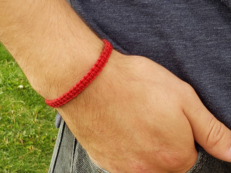 May include: A red crocheted bracelet on a person's wrist.