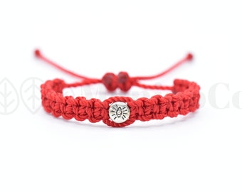 May include: Red braided bracelet with a silver charm featuring a sun with an eye inside.