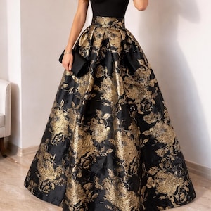 May include: A formal black gown with a sweetheart neckline and a full skirt. The skirt features a gold floral brocade pattern. The dress has a fitted bodice and a floor-length skirt, suitable for special occasions.