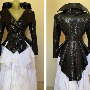 May include: A black sequined jacket with a wide collar and long sleeves, combined with a white layered skirt. The jacket has a V-neck and button closure. The outfit is displayed on a mannequin.