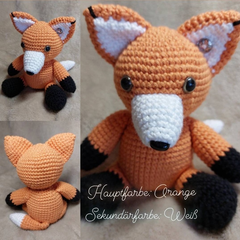 May include: A crocheted orange fox plush toy with white accents on the ears, nose, and paws. The toy has black eyes and a black nose. The text "Hauptfarbe: Orange Sekund&auml;rfarbe: Wei&szlig;" is visible in the image.