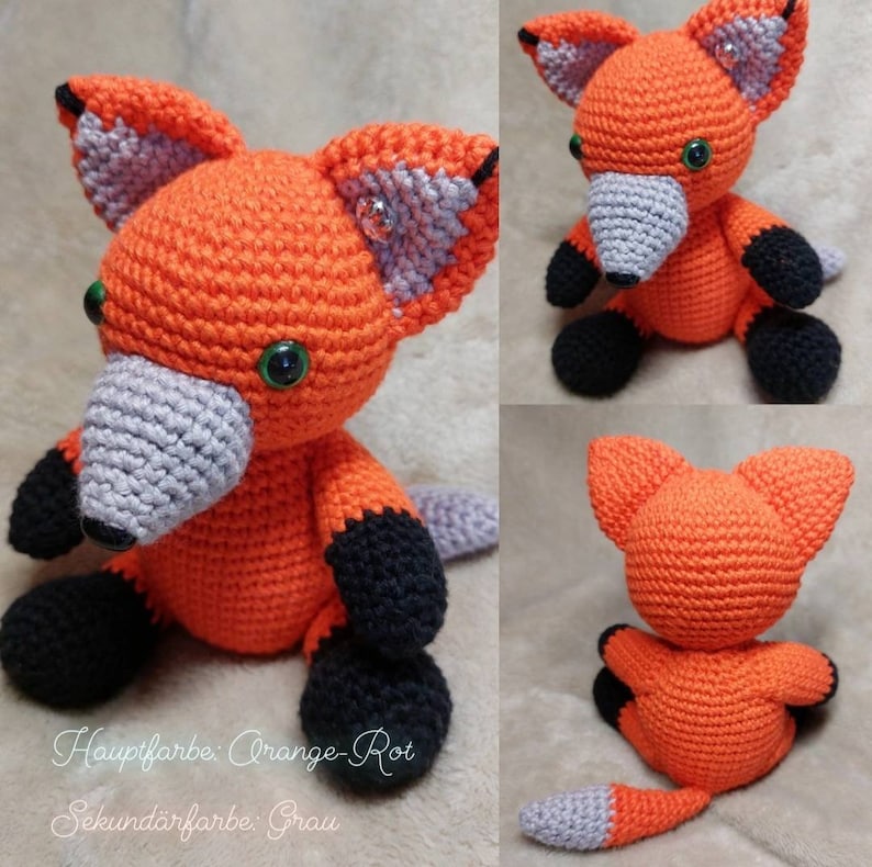 May include: A crocheted fox plush toy made with orange, grey and black yarn. The fox is sitting with its tail curled behind it. The text on the image reads "Hauptfarbe: Orange-Rot Sekund&auml;rfarbe: Grau".