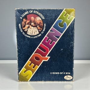 May include: A vintage board game box with the word "SEQUENCE" in a colorful diagonal design. The box is dark blue with text that reads "A Game of Strategy" and "Minutes to Learn, A Lifetime to Master."