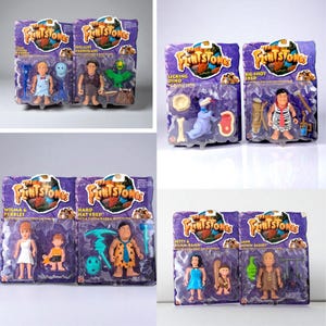 May include: A collection of vintage Flintstones action figures in their original packaging. The figures include characters like Fred, Wilma, and Dino, each with accessories. The packaging is purple and features the Flintstones logo.