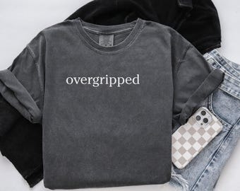May include: A dark gray t-shirt with the word "overgripped" printed in white on the front.