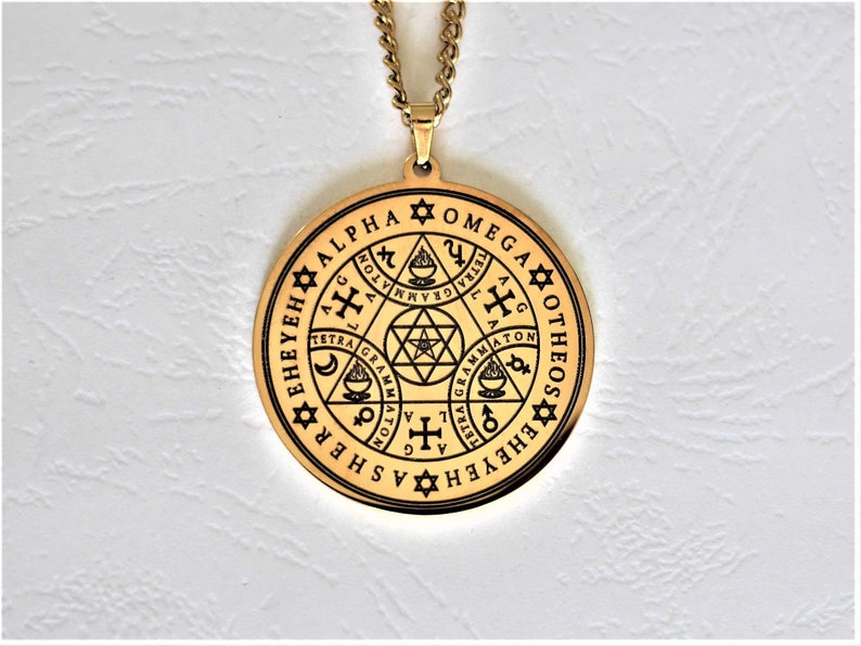May include: Gold pendant necklace with a circular design featuring a star of David, a cross, and other symbols. The pendant is inscribed with the words "EHEYEH EHEYEH ASCHER SHEH ALPHA OTHEOS OMEGA".