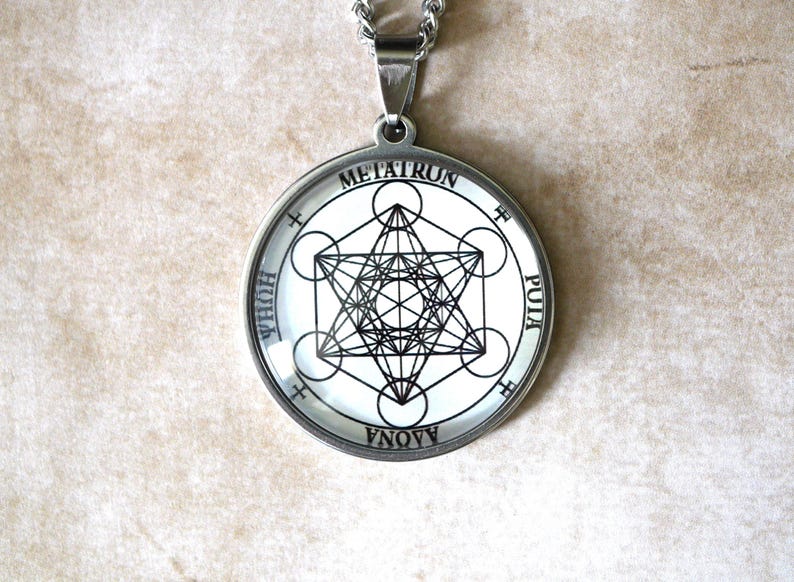 K&ouml;nnte beinhalten: Ein runder, silberfarbener Anh&auml;nger an einer Kette mit einem schwarz-wei&szlig;en geometrischen Metatron-W&uuml;rfel-Design. Der &auml;u&szlig;ere Rand zeigt den Text METATRUN, PUIA, AAONA und HUHA in schwarzen Gro&szlig;buchstaben auf wei&szlig;em Hintergrund.