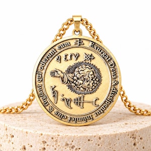 Puede incluir: Un colgante circular dorado con cadena que presenta un diseño en relieve de una mano y un rostro barbudo rodeado de rayos. El borde contiene el texto en latín Exurgat Deus & dissipentur inimici eius & fugiant qui oderunt eum.