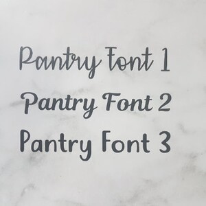 K&ouml;nnte beinhalten: Drei verschiedene Schriftstile f&uuml;r das Wort "Pantry" werden auf einem wei&szlig;en Marmorhintergrund gezeigt. Die Schriften sind alle im Kursiv-Stil.
