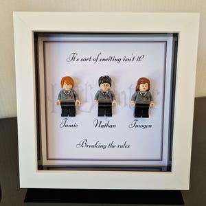 Może przedstawiać: Biała ramka z białym passe-partout i białym tłem. Ramka zawiera trzy minifigurki Lego postaci z Harry'ego Pottera. Minifigurki są oznaczone jako "Jamie", "Nathan" i "Imogen". Tekst "It's sort of exciting isn't it?" i "Breaking the rules" jest wydrukowany na tle.