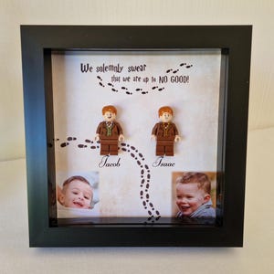 Może przedstawiać: Oprawione pudełko z dwoma figurkami Lego i dwoma zdjęciami. Tekst "We solemnly swear that we are up to NO GOOD!" jest wydrukowany nad figurkami. Imiona "Jacob" i "Isaac" są wydrukowane poniżej.