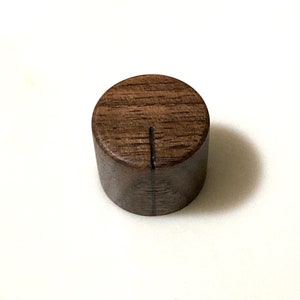 May include: A round wooden knob with a dark brown finish and a single line carved into the top.