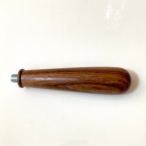 May include: A wooden handle with a silver metal threaded end. The handle is brown with a wood grain pattern.