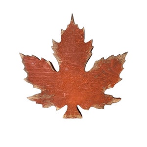 May include: A red wooden maple leaf with a distressed finish. The leaf is a simple silhouette with no details.