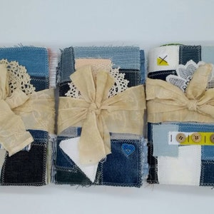 May include: Three handmade journals with denim and fabric covers, tied with a beige ribbon and decorated with lace and buttons.