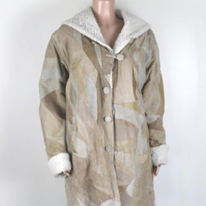May include: A long, beige patchwork suede coat with a white faux fur collar and cuffs. The coat has a button closure and a relaxed fit.