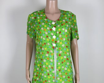 May include: A green dress with a floral print featuring small, colorful flowers. The dress has a button-up front and short sleeves.