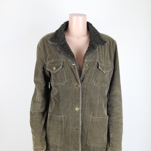 May include: A green corduroy jacket with a brown faux fur collar. The jacket has a button closure and two large pockets on the front.