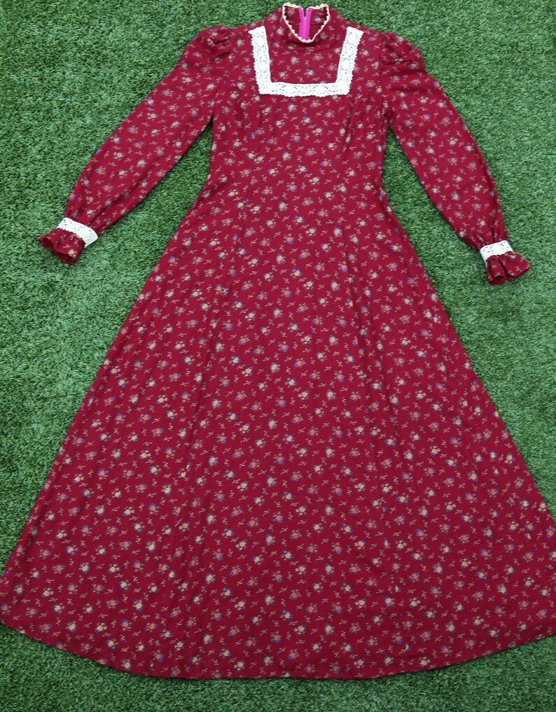 May include: A long-sleeved, red floral dress with a white lace collar and cuffs. The dress has a fitted bodice and a flowing skirt.
