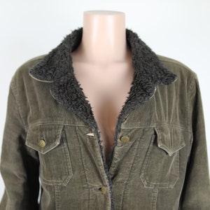 May include: A green corduroy jacket with a brown faux fur collar. The jacket has a button closure and two front pockets.