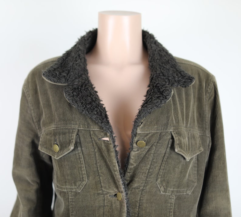 May include: A green corduroy jacket with a brown faux fur collar. The jacket has a button closure and two front pockets.