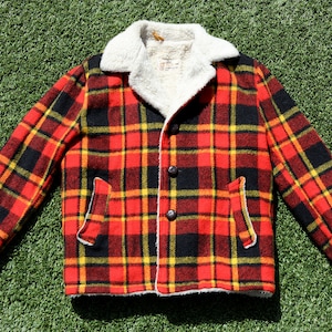 May include: A red, black and yellow plaid jacket with a white faux fur collar. The jacket has a button fastening and two pockets.