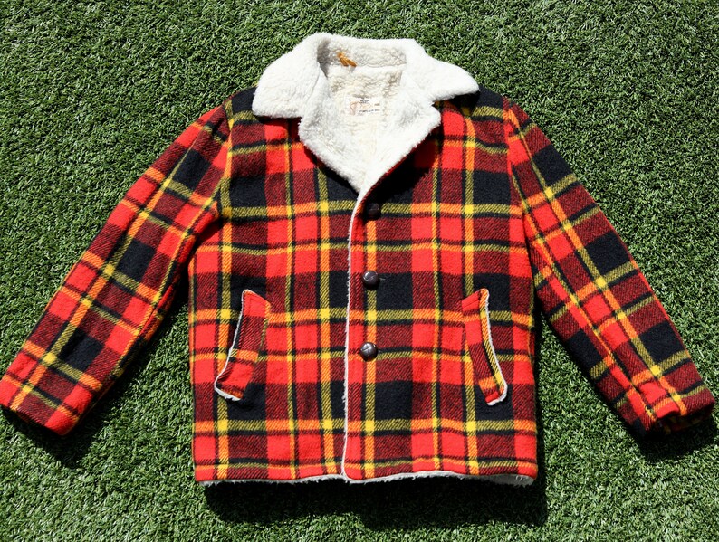 May include: A red, black and yellow plaid jacket with a white faux fur collar. The jacket has a button fastening and two pockets.