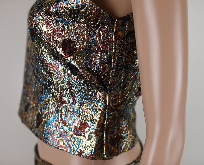 May include: A strapless top with a gold, blue, and red paisley pattern. The top is made of a shiny fabric and has a fitted bodice.